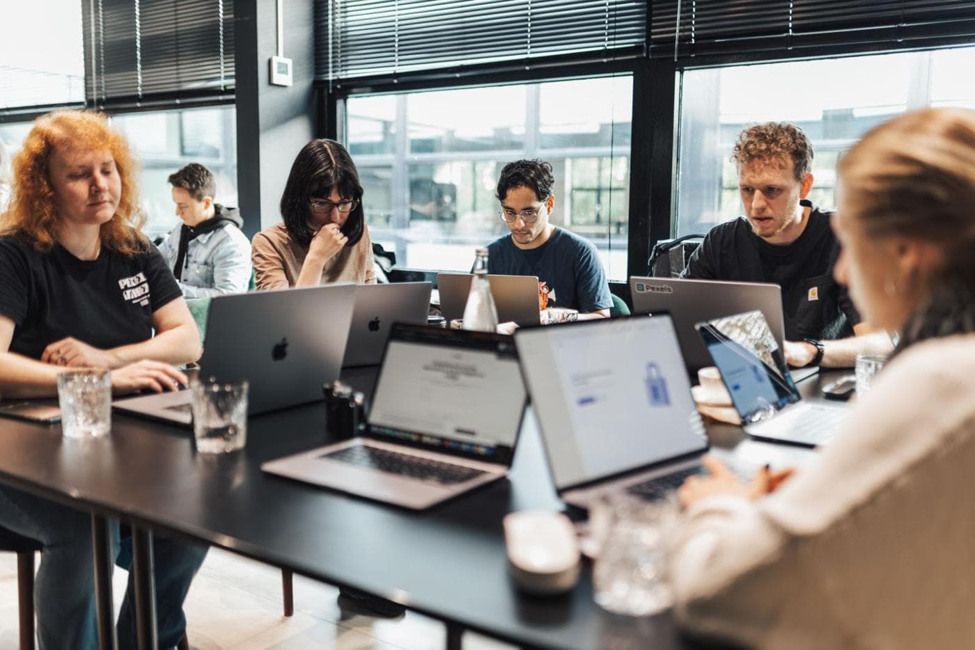 A team of attendees working on laptops at a workshop table